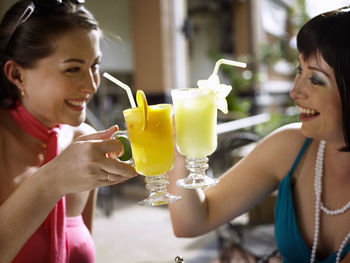 Happy friends toasting drinks while sitting on table at restaurant