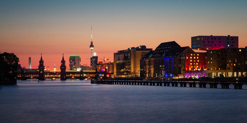 Illuminated buildings in city at sunset