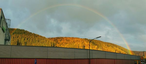 Low angle view of rainbow over building against sky