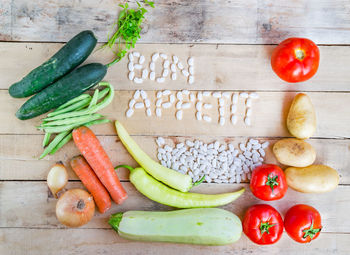 Directly above of text made from lima beans by vegetables on wooden table