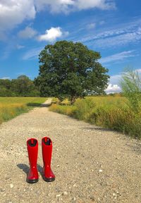 Red boots on pathway against sky