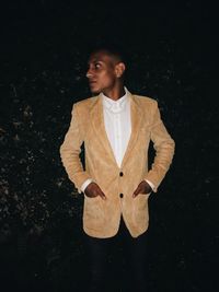 Young man in suit standing against black background