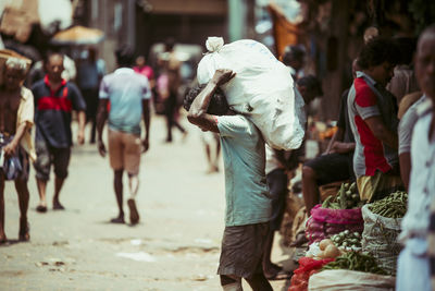 Rear view of people walking on street in city