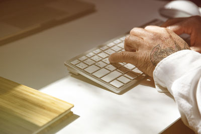 Hands of a tattooed man on the keyboard of a laptop