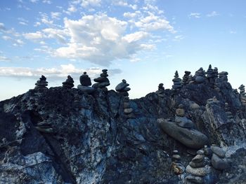 Low angle view of birds perching on rock against sky