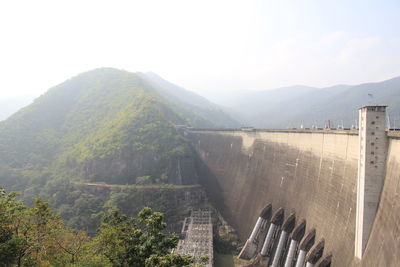 Scenic view of dam and mountains against sky