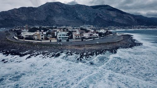 Scenic view of sea by mountains against sky