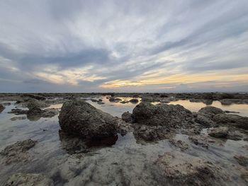 Rocks on shore against sky during sunset