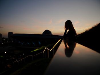 Silhouette woman on bridge against sky during sunset