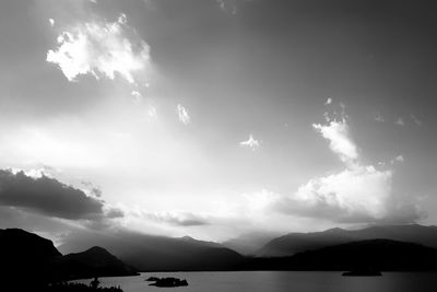 Scenic view of lake and silhouette mountains against sky