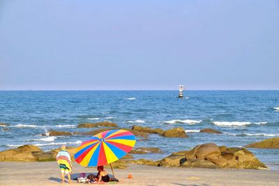 People at beach against clear sky