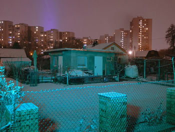 Illuminated buildings by swimming pool against sky at night