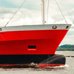 Red boat moored at beach against sky