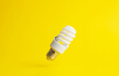 Close-up of light bulb against yellow background