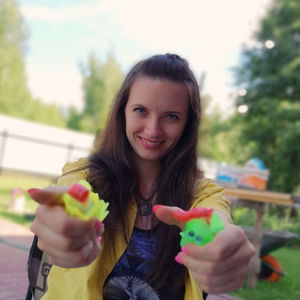 Portrait of smiling mid adult woman holding toys while standing against sky in park