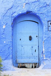 Close-up of blue door on weathered wall