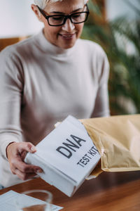 Midsection of man holding paper with text on table