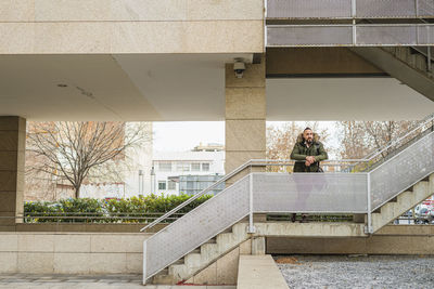 Bearded hipster man relaxing on stairs in a building complex