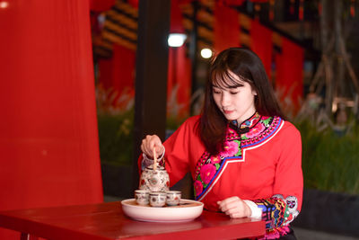 Woman looking away while sitting on table