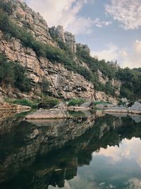 Rock formation by lake against sky