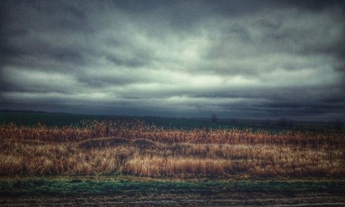 Scenic view of field against storm clouds