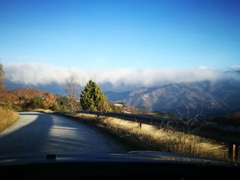 Road amidst mountains seen through car windshield