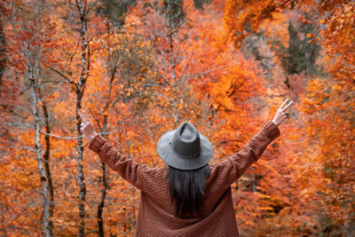 Rear view of woman with outstretched arms. autumn, fall, forest, adventure.