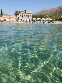 Sea by buildings against mountains