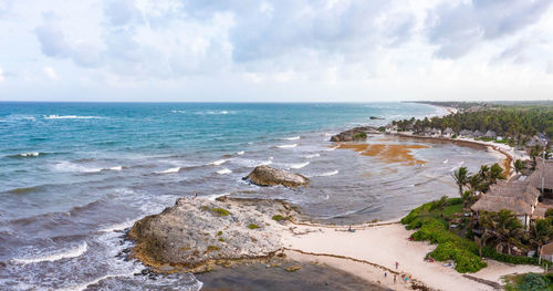 Aerial tulum coastline by the beach with a magical caribbean sea and small huts by the coast.