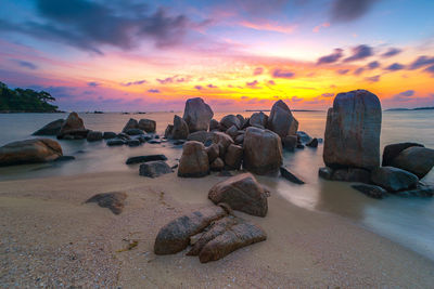 Rocks on beach against sky during sunset