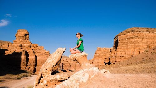 Low angle view of young woman sitting on rock