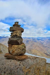 Stack of stones on rock against sky