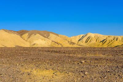 Scenic view of desert against clear blue sky