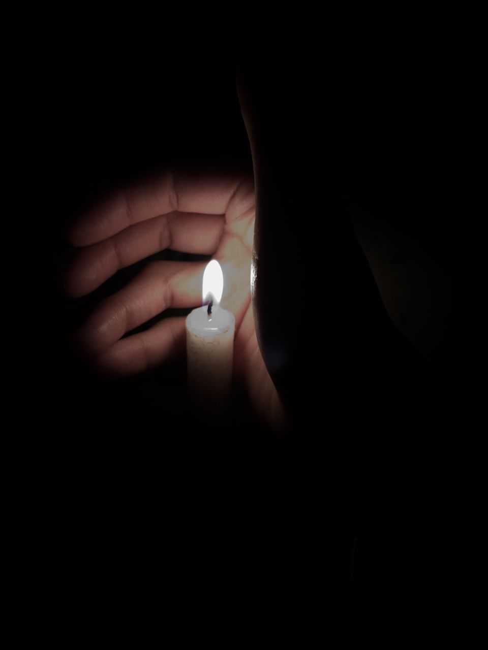 CLOSE-UP OF HAND HOLDING LIT CANDLE