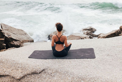 Rear view of woman sitting on beach