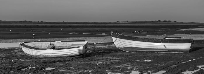 Boat moored on beach against sky