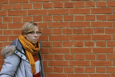 Portrait of woman standing against brick wall