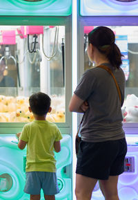 Rear view of woman with son standing by toys at store