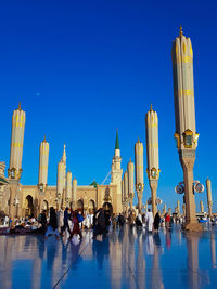 Group of people in front of building against clear blue sky