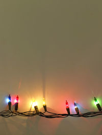 Close-up of illuminated string light over yellow background