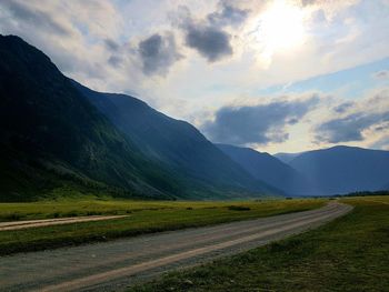 Scenic view of road by mountains against sky