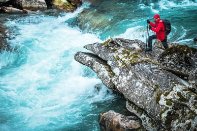 Man climbing on rock at riverbank