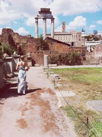 Rear view of woman standing on walkway at roman forum during sunny day