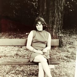 Young woman sitting on tree trunk in forest