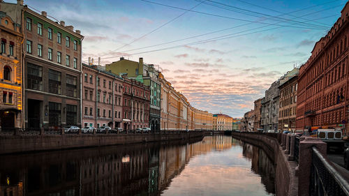 Bridge over canal amidst buildings in city against sky