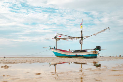 Fishing boat on beach against sky