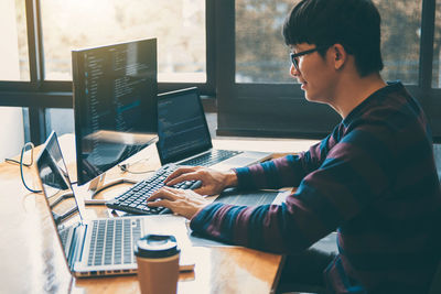 Side view of businessman using computer at desk in office