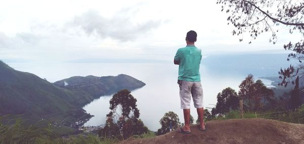 Rear view of man looking at mountains against sky