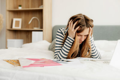 Young woman using mobile phone on bed at home