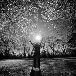 Rear view of man standing on field against trees